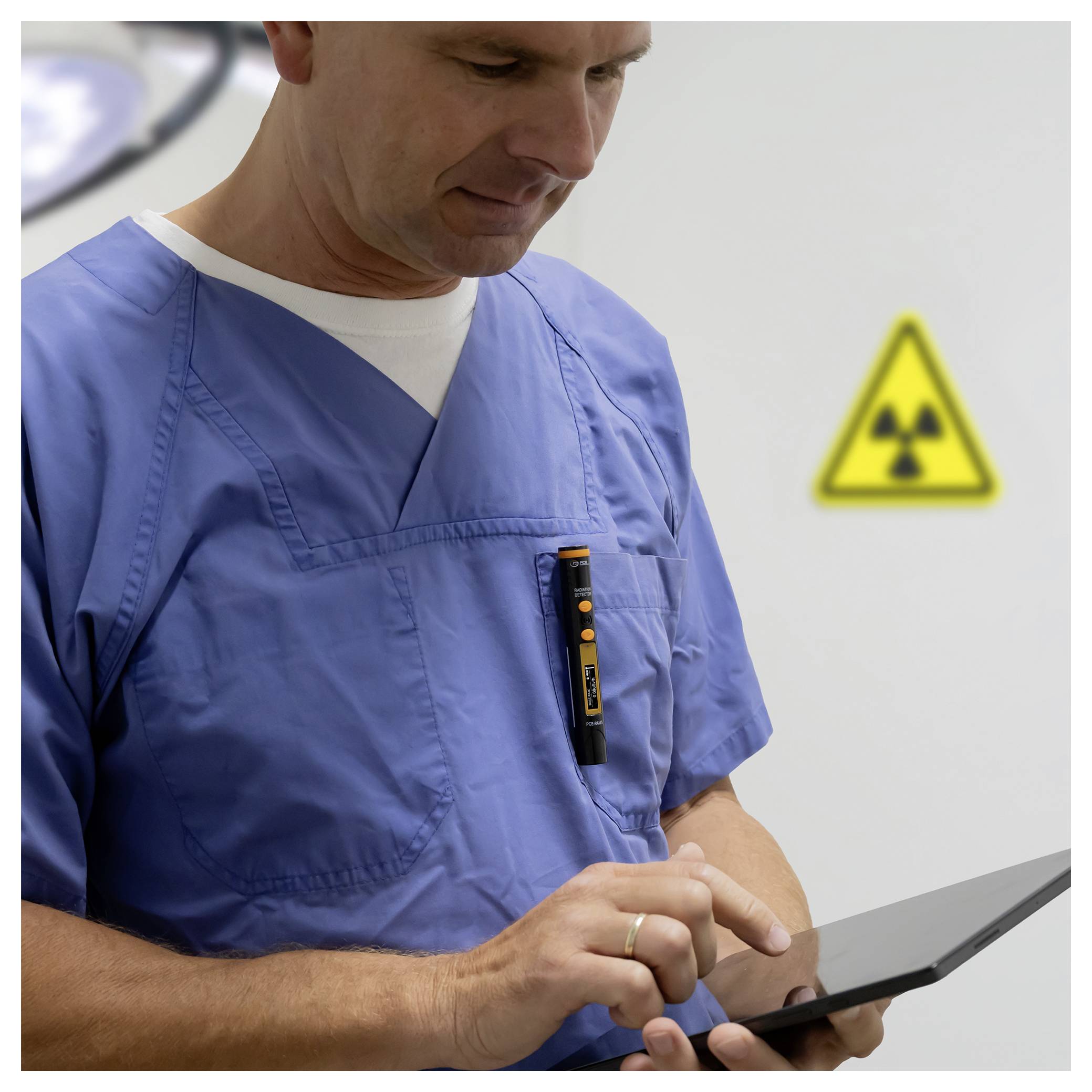 Gesundheitsarbeiter in blauen Kasacks, der ein Tablet benutzt, mit einem Strahlenwarnzeichen im Hintergrund.