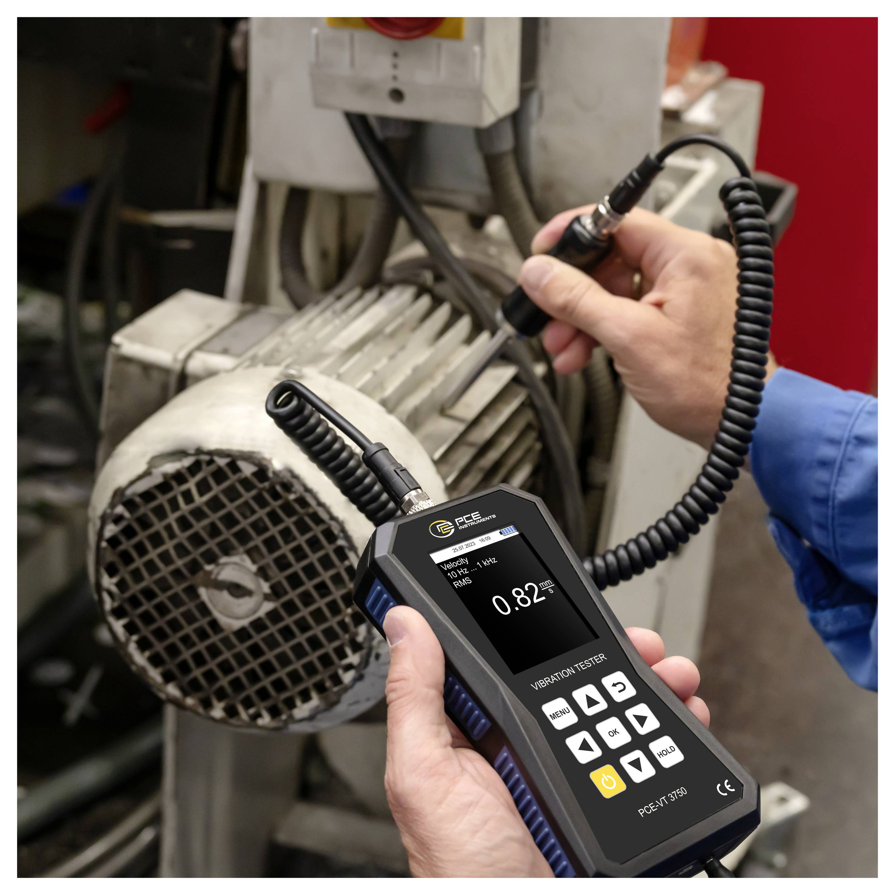 Techniker, der ein tragbares Vibrationsprüfgerät an einem Elektromotor einsetzt, um Maschinenvibrationen zu messen und auf Fehler zu prüfen.
