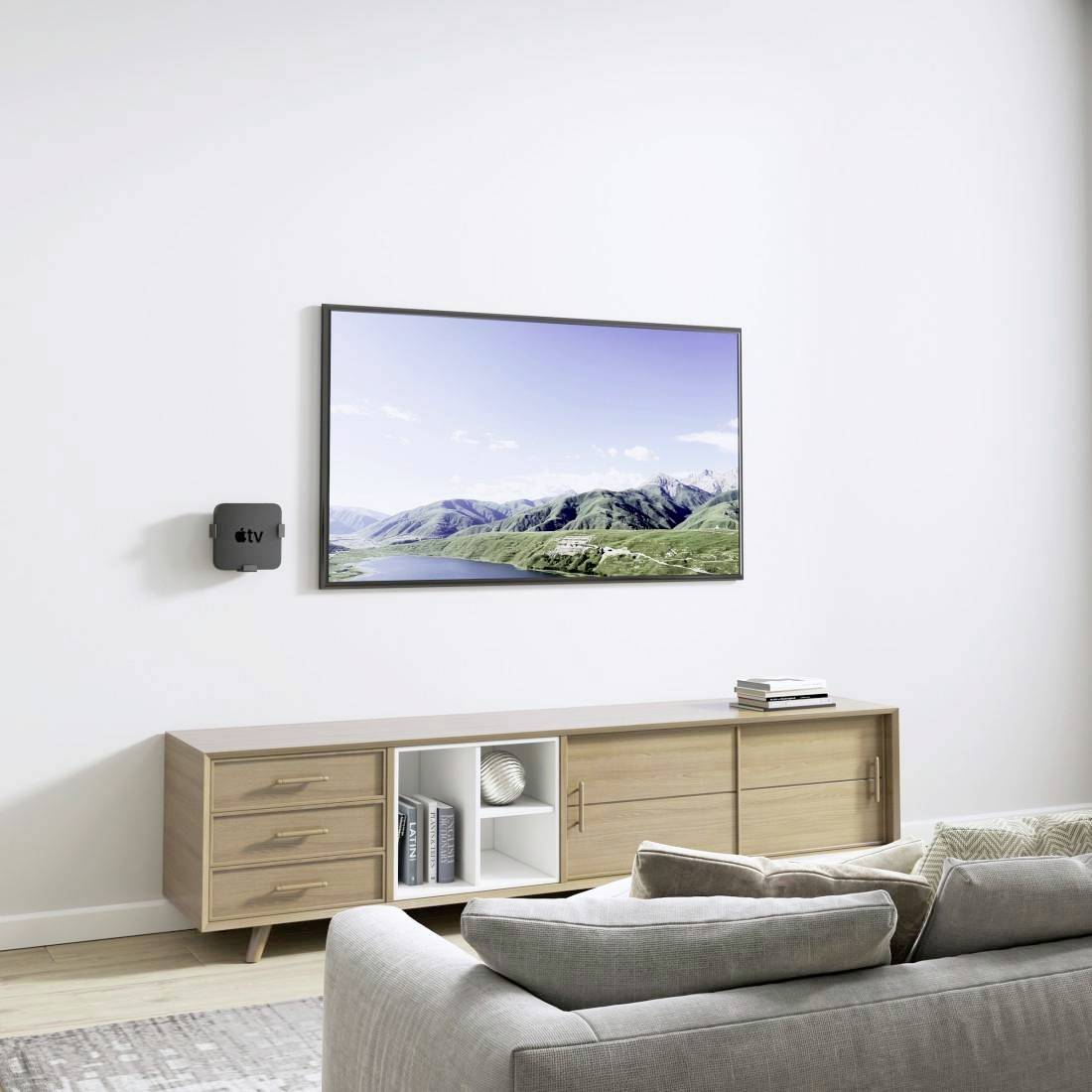 Ein Wohnzimmer mit einem Sofa, einem hölzernen TV-Schrank und einem Flachbildfernseher an der Wand, der eine Landschaft zeigt.