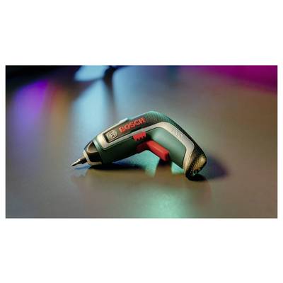 Ein grüner Bosch-Akkuschrauber liegt auf einem Tisch. Im Hintergrund sind unscharfe bunte Lichter zu sehen.
