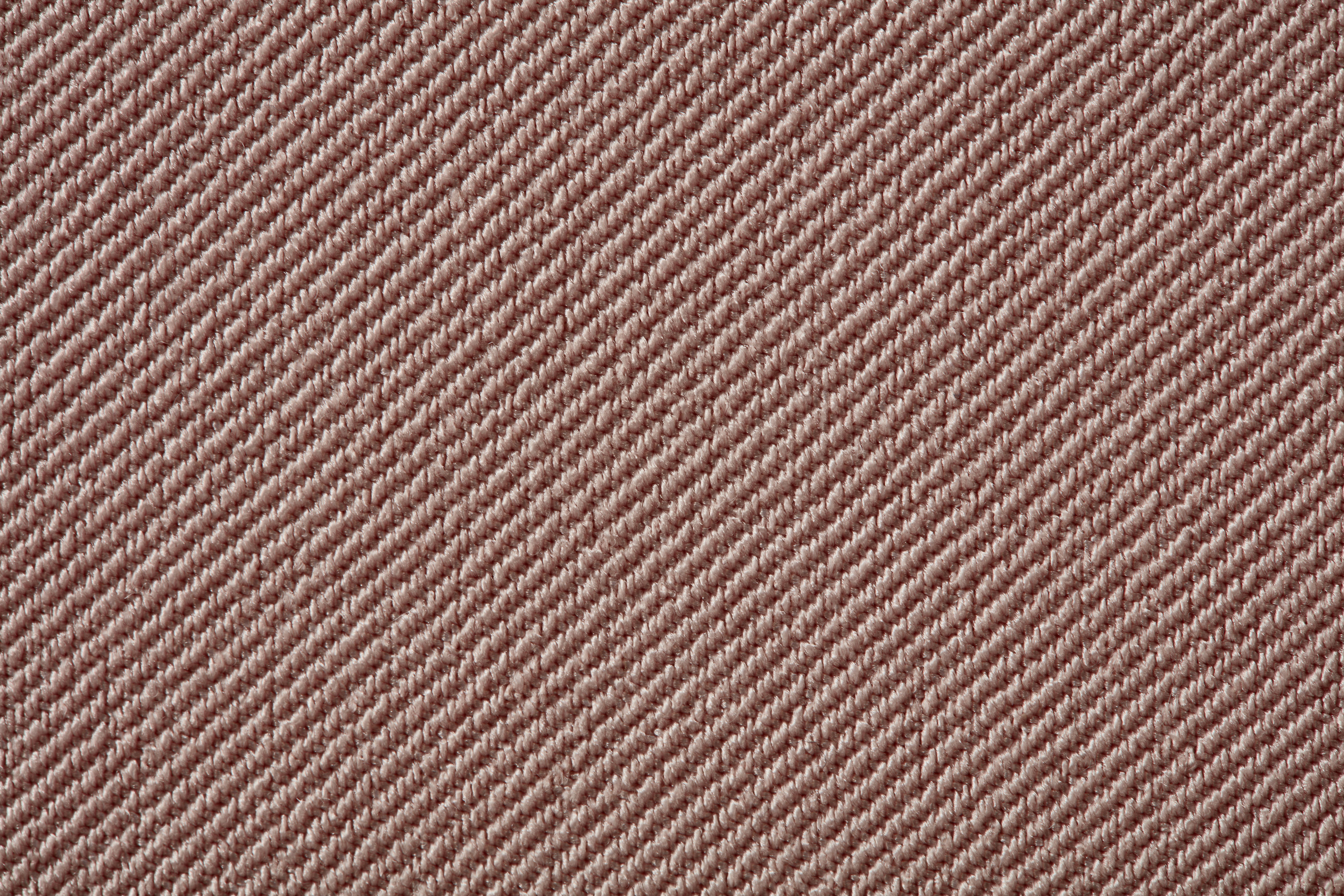 Nahaufnahme einer Textilstruktur mit diagonalen, gleichmäßigen Linien in einem hellen Braunton.