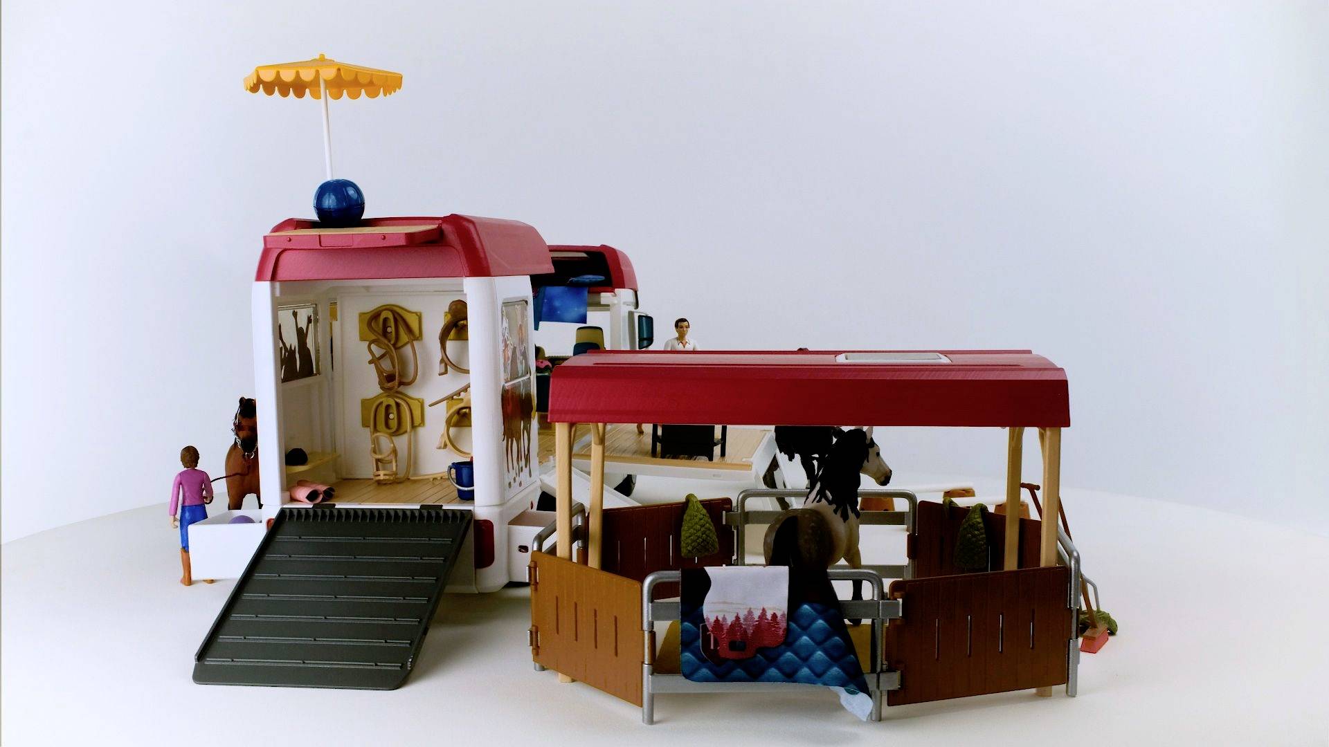 Spielzeug-Reisebus mit offenem Dach, Figuren im Inneren. Links ist eine Rampe, rechts Sitze, einige Figuren erholen sich.