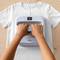 Person bügelt ein weißes T-Shirt mit einem Bügeleisen, das digital 330 Grad Fahrenheit und 30 Sekunden anzeigt.