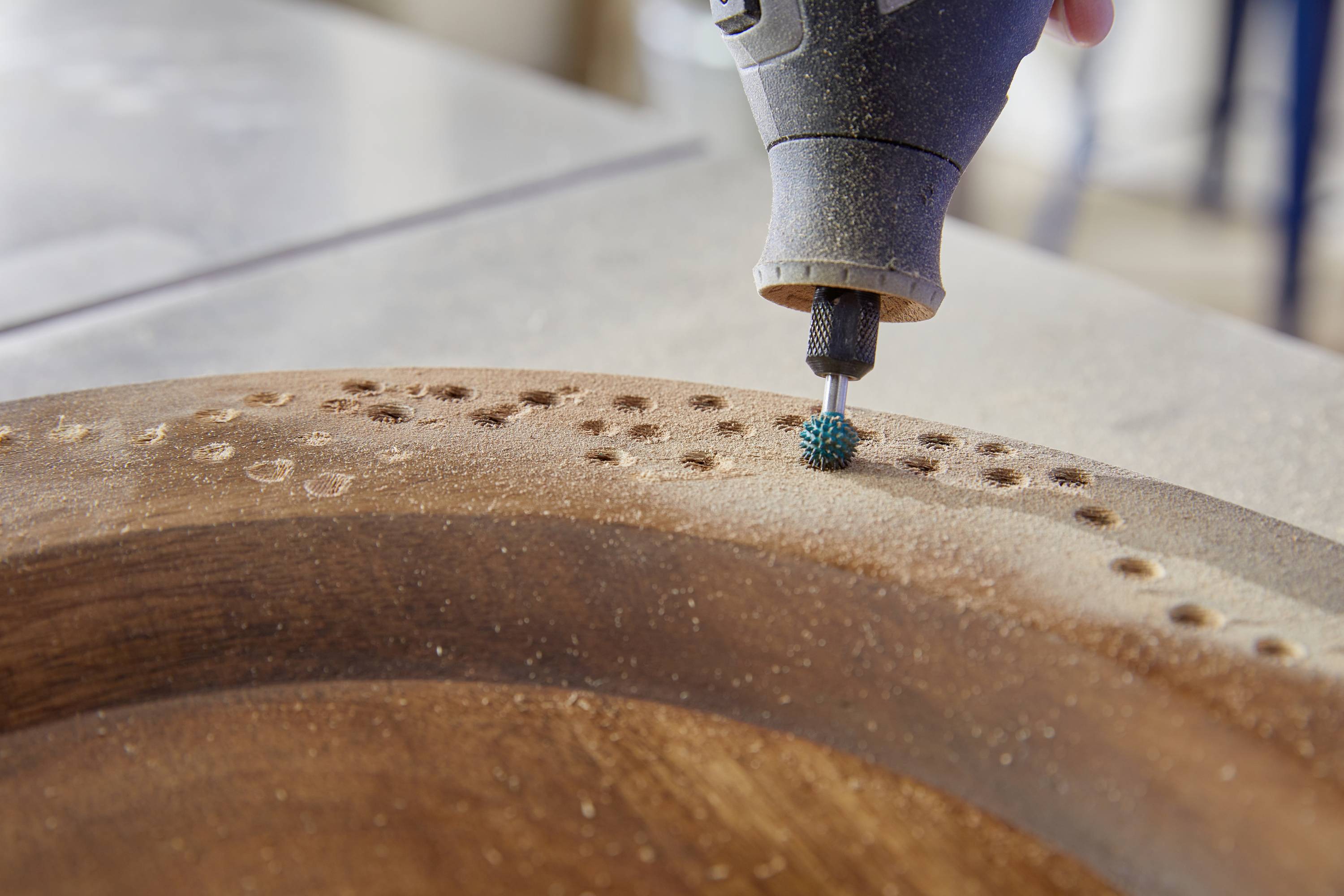 Eine Fräse bearbeitet kreisförmige Muster auf einem Holzbrett. Nahaufnahme zeigt die Details des Holzbearbeitungsprozesses.