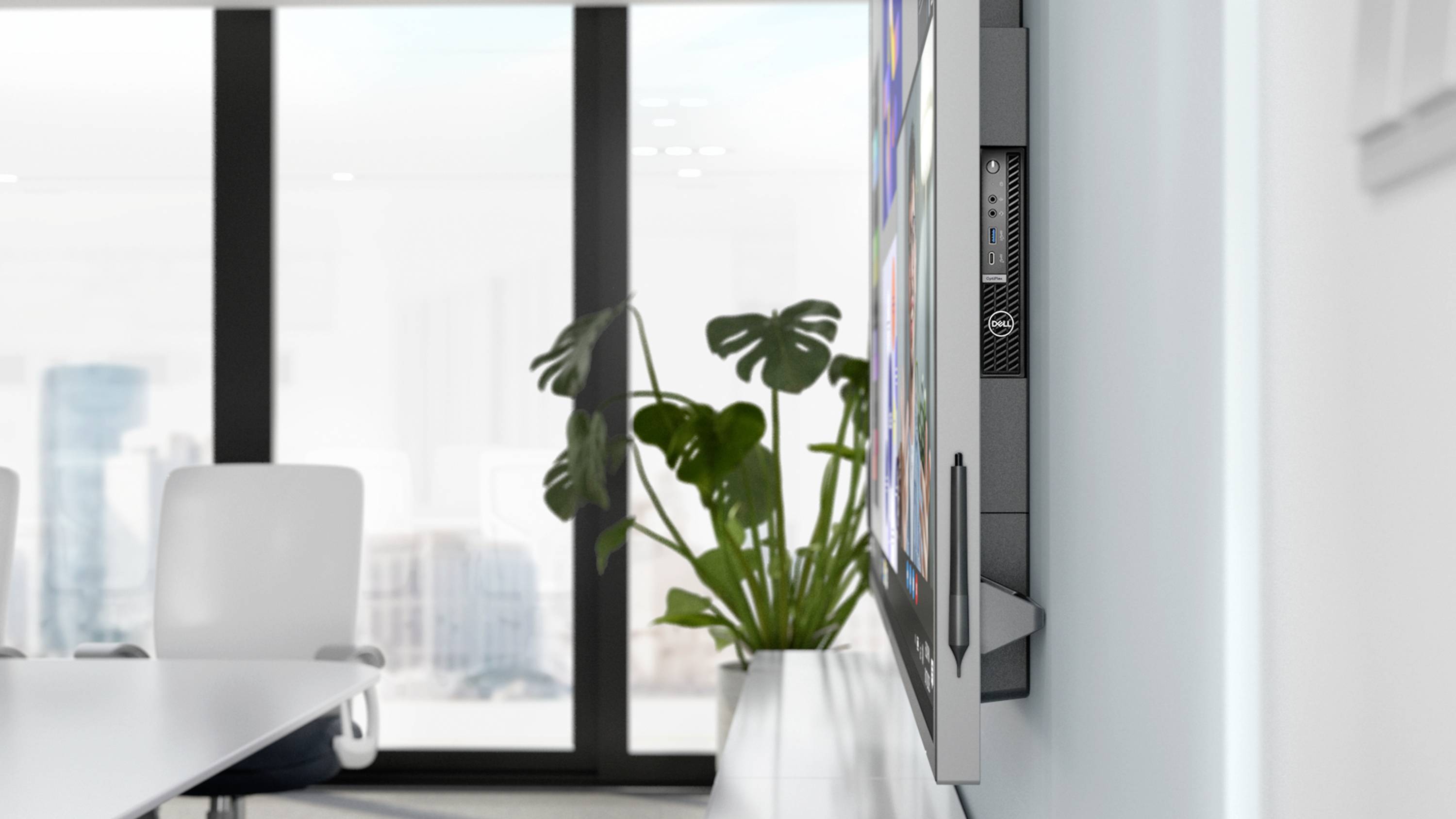 Besprechungsraum mit großem Bildschirm, der an der Wand montiert ist. Im Hintergrund sind große Fenster mit Stadtansicht zu sehen.