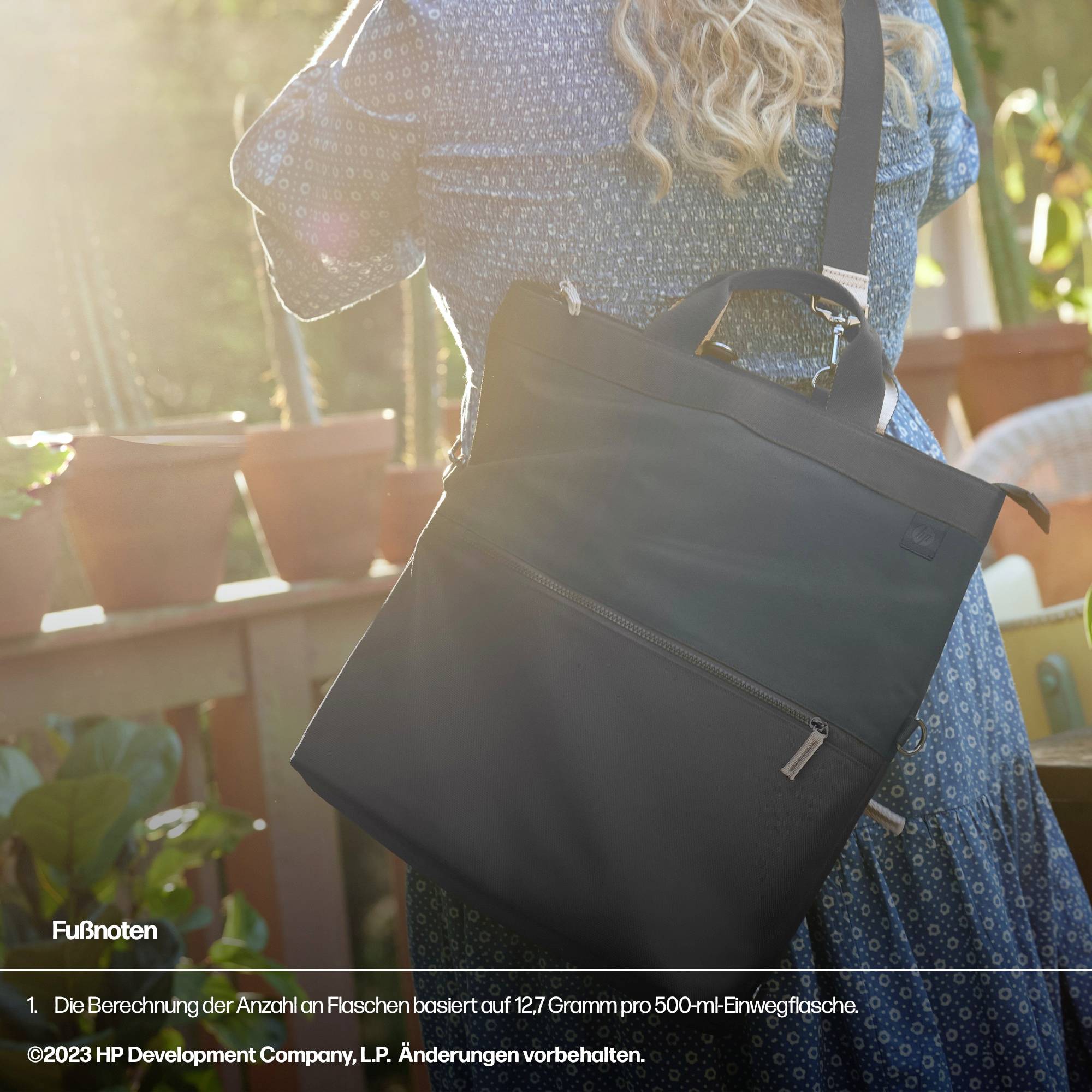 Eine Person trägt eine schwarze Tasche auf der Schulter. Im Hintergrund sind unscharf Blätter zu sehen.