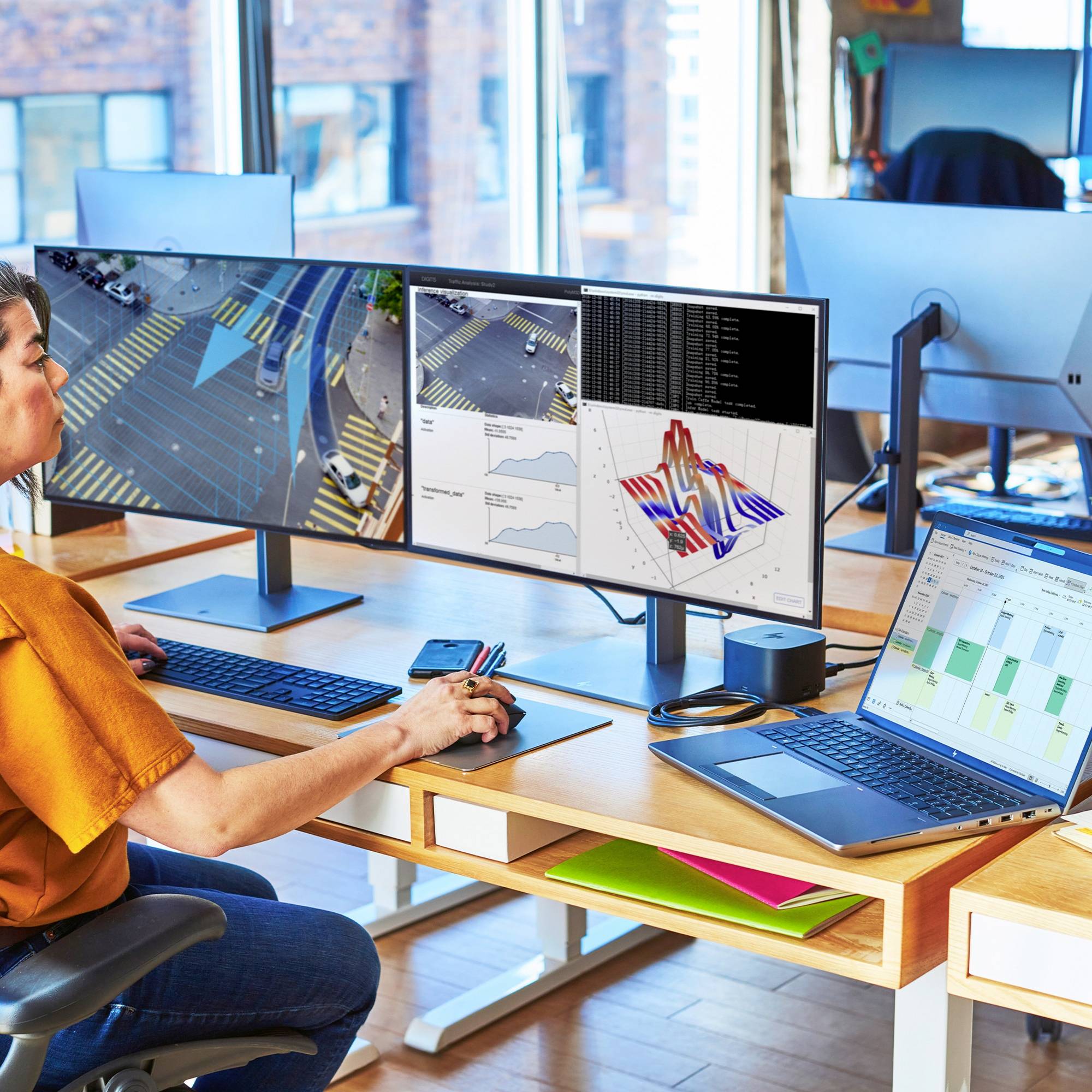 Ein Mensch arbeitet an einem Schreibtisch mit mehreren Bildschirmen, die Verkehrs- und Datenanalysen zeigen. Im Hintergrund ist ein Büro sichtbar.