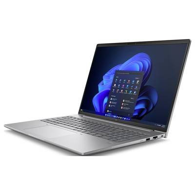 Ein geöffneter Laptop zeigt den Windows-Startbildschirm mit verschiedenen Anwendungen auf einem Tisch. Das Gerät ist silberfarben.