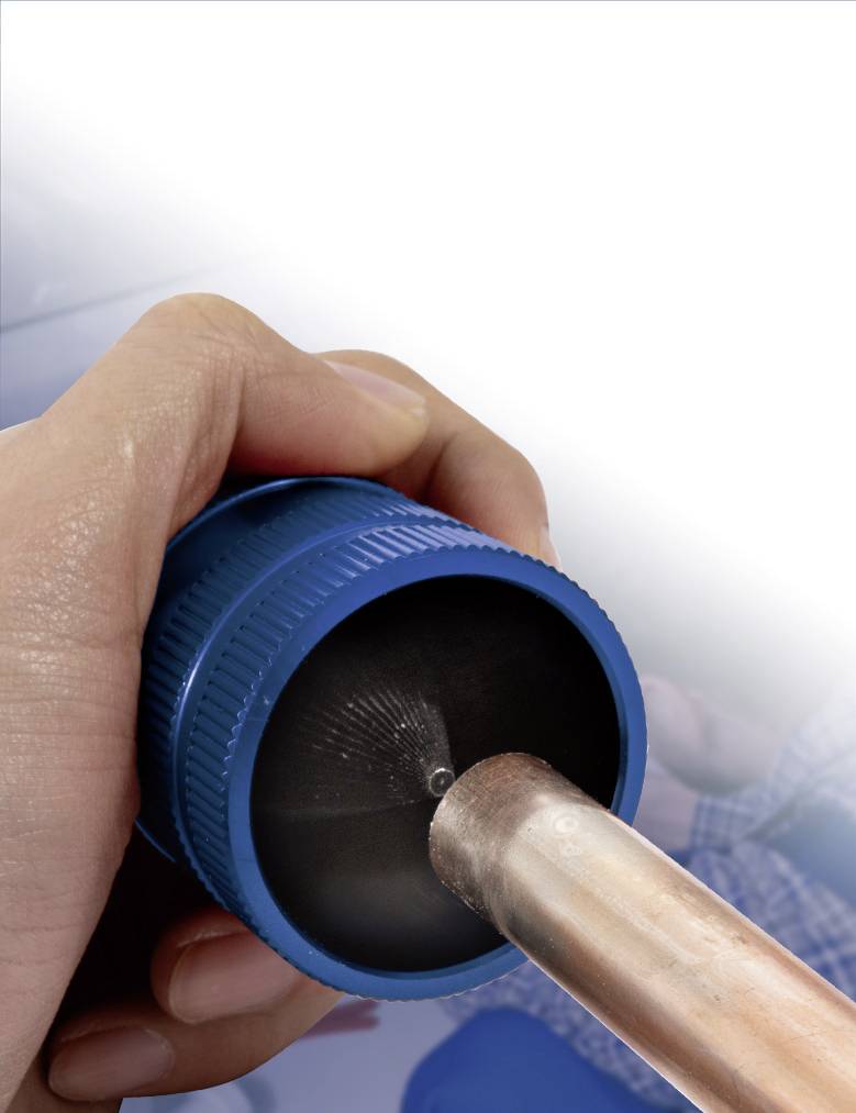 Eine Hand hält ein blaues Werkzeug, das ein Kupferrohr schneidet.