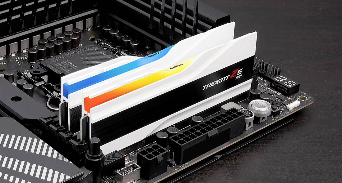 Nahaufnahme eines Motherboards mit installierten RAM-Riegeln, die farblich gestreift sind. Details der Anschlüsse und Kondensatoren sichtbar.
