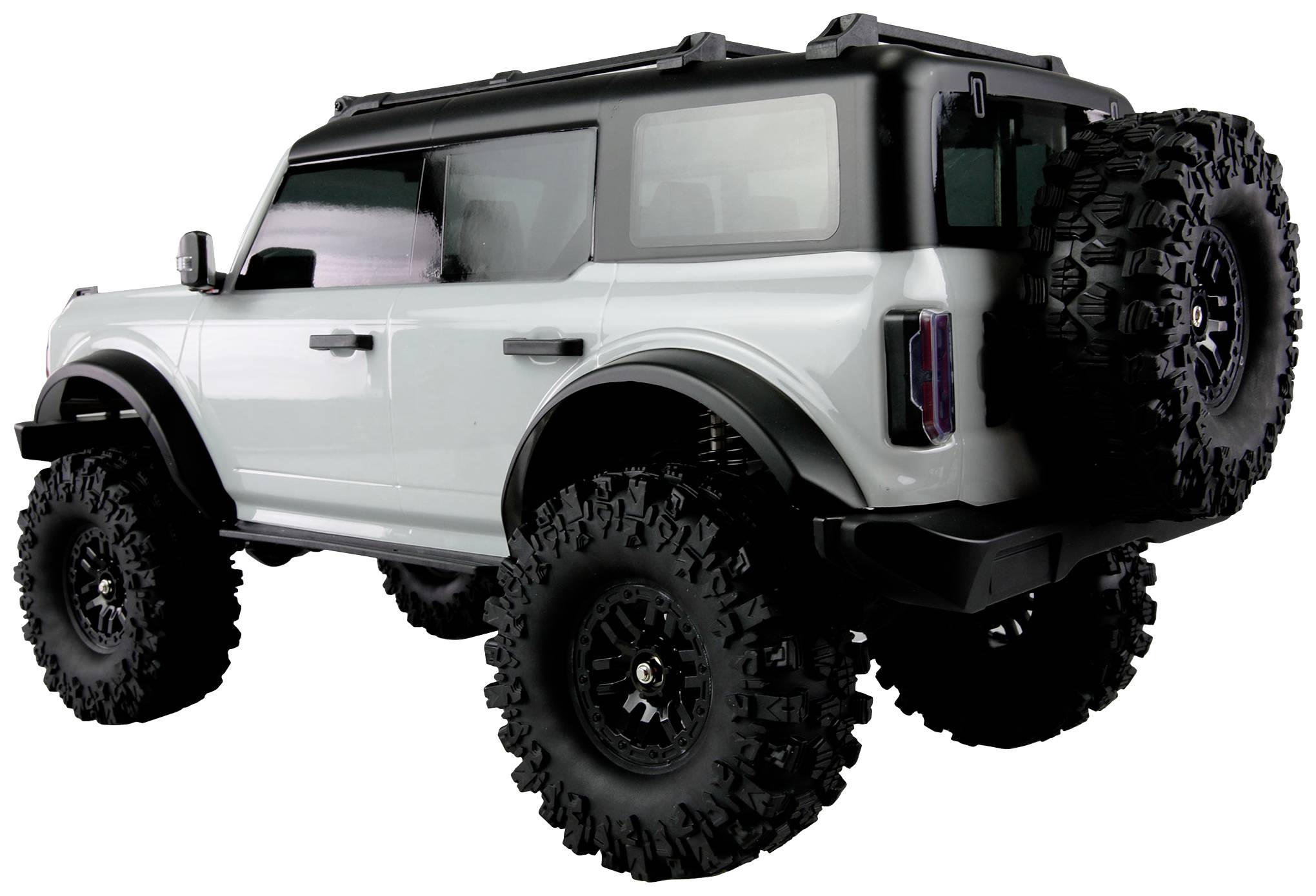 Ein weißes Modellauto mit großen, griffigen Reifen, robustem Außendesign und Reserverad am Heck, steht auf einer ebenen Fläche.