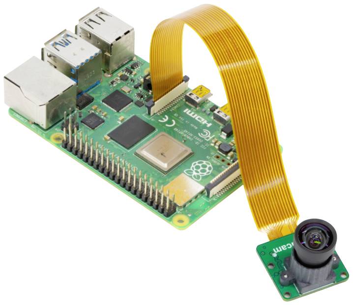Ein kleines, grünes, rechteckiges Motherboard mit Anschlüssen, das über ein flexibles, orangefarbenes Kabel mit einer kleinen Kamera verbunden ist.