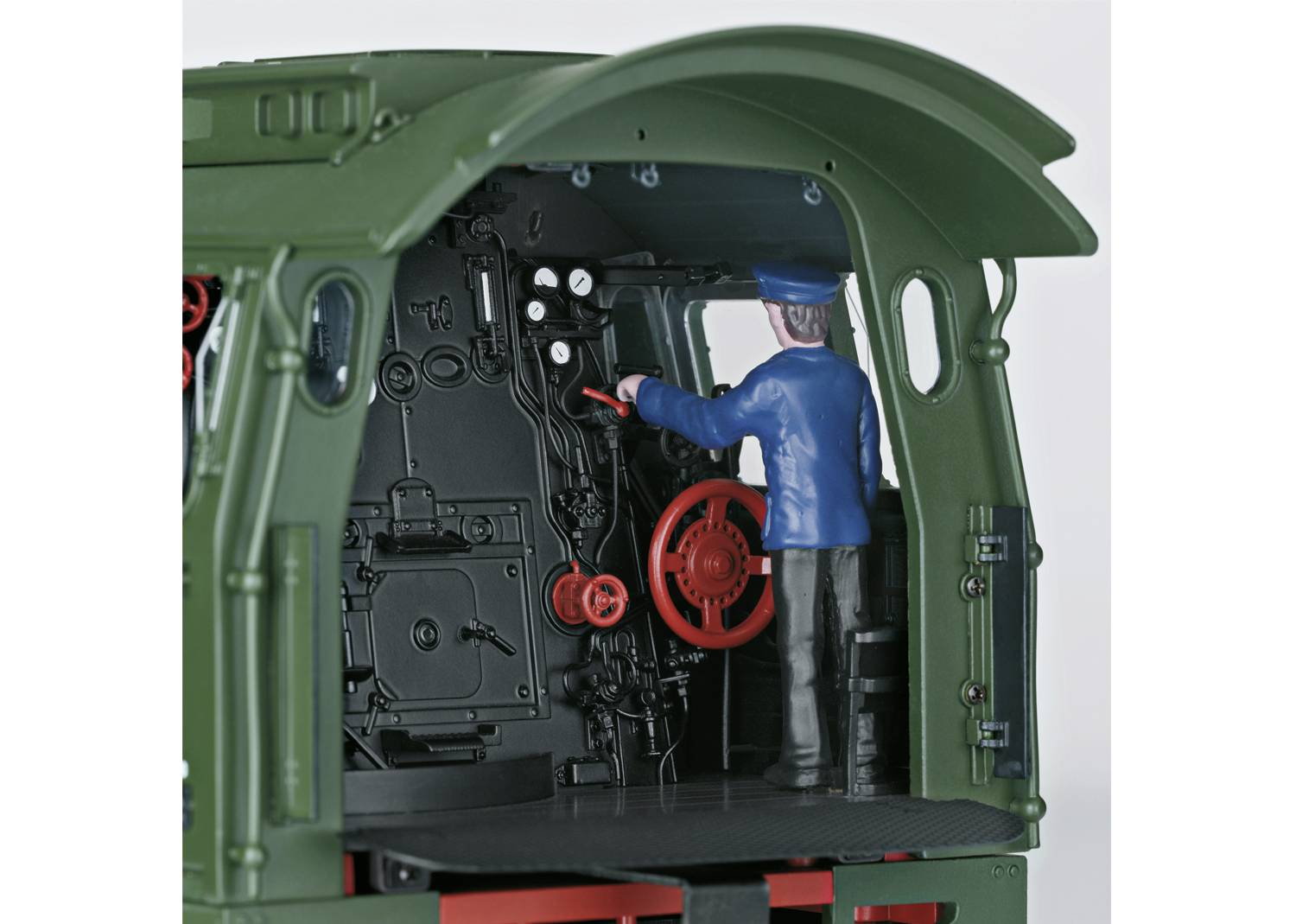 Eine Modellfigur in einer grünen Lokomotive. Die Figur trägt eine blaue Uniform und steht im Cockpit, hält das Rad der Steuerung.