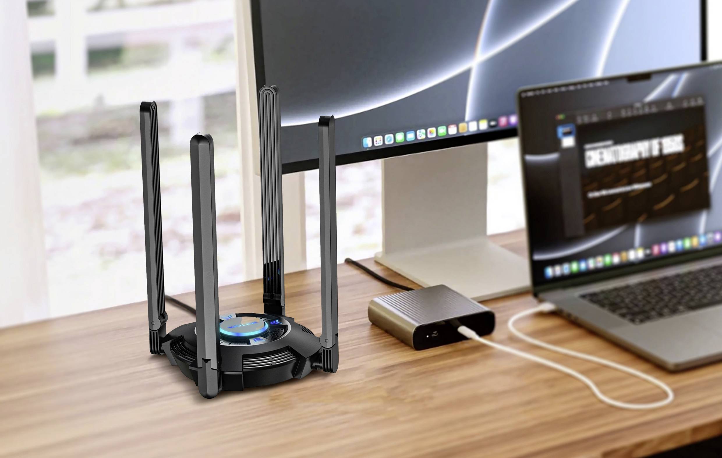 Ein moderner WLAN-Router mit mehreren Antennen steht auf einem Schreibtisch neben einem Computerbildschirm und einem Laptop.