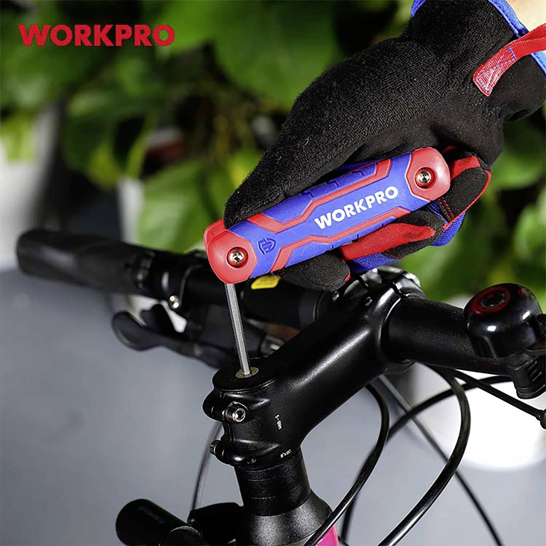 Eine Person mit Handschuhen justiert mit einem Schraubendreher aus einem Multitool ein Fahrrad, umgeben von Pflanzen.