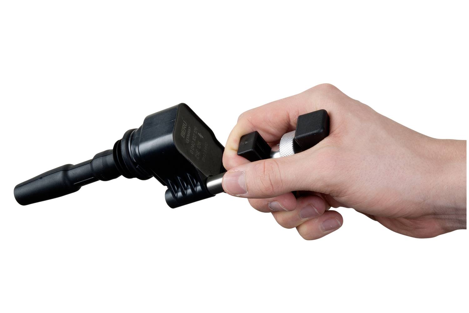 Eine Hand hält ein Zündspulenausziehwerkzeug, das für die Entfernung von Zündspulen bei Fahrzeugmotoren verwendet wird.