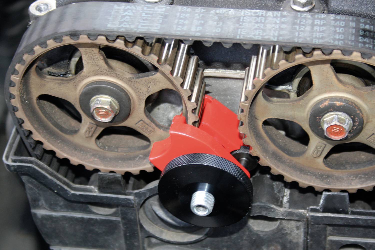 Zwei rostige Zahnräder mit einem roten Halter in einer Motoranordnung, zeigen mechanische Verbindung und Funktion.