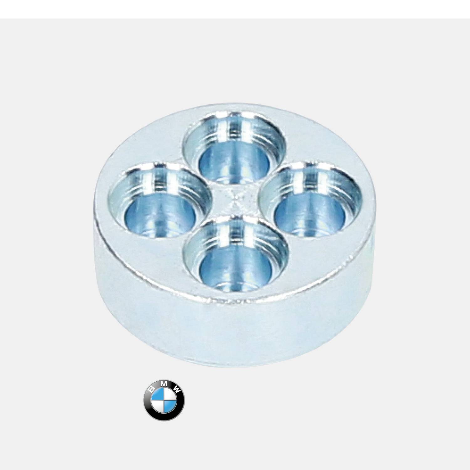 Ein rundes Metallteil mit vier Löchern auf der Oberseite, darunter das BMW-Logo.