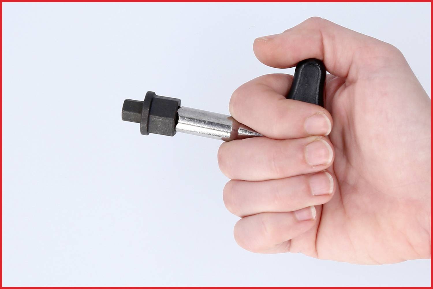 Eine Hand hält einen schwarzen und silbernen Kurbelabzieher, ein Werkzeug zum Entfernen von Fahrradkurbeln.