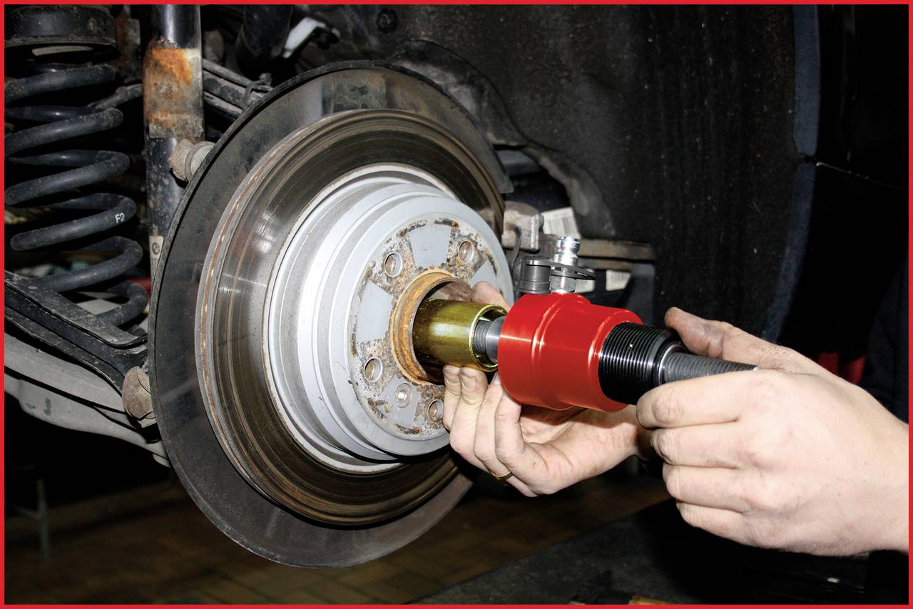 'Nahaufnahme einer Autobremsanlage, bei der ein Mechaniker ein Werkzeug benutzt, um ein Teil des Bremssystems zu warten oder zu reparieren.'
