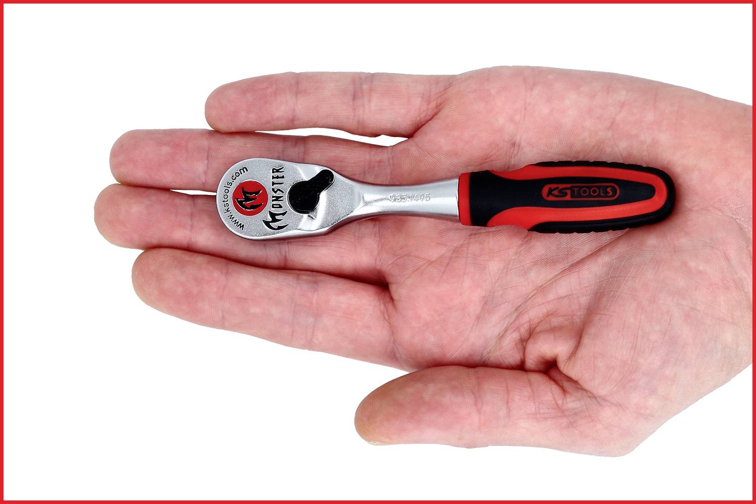 Eine kleine Knarre, etwa handgroß, liegt auf einer offenen Handfläche. Die Knarre hat einen schwarzen und roten Griff und eine glänzende, silberne Ratsche.