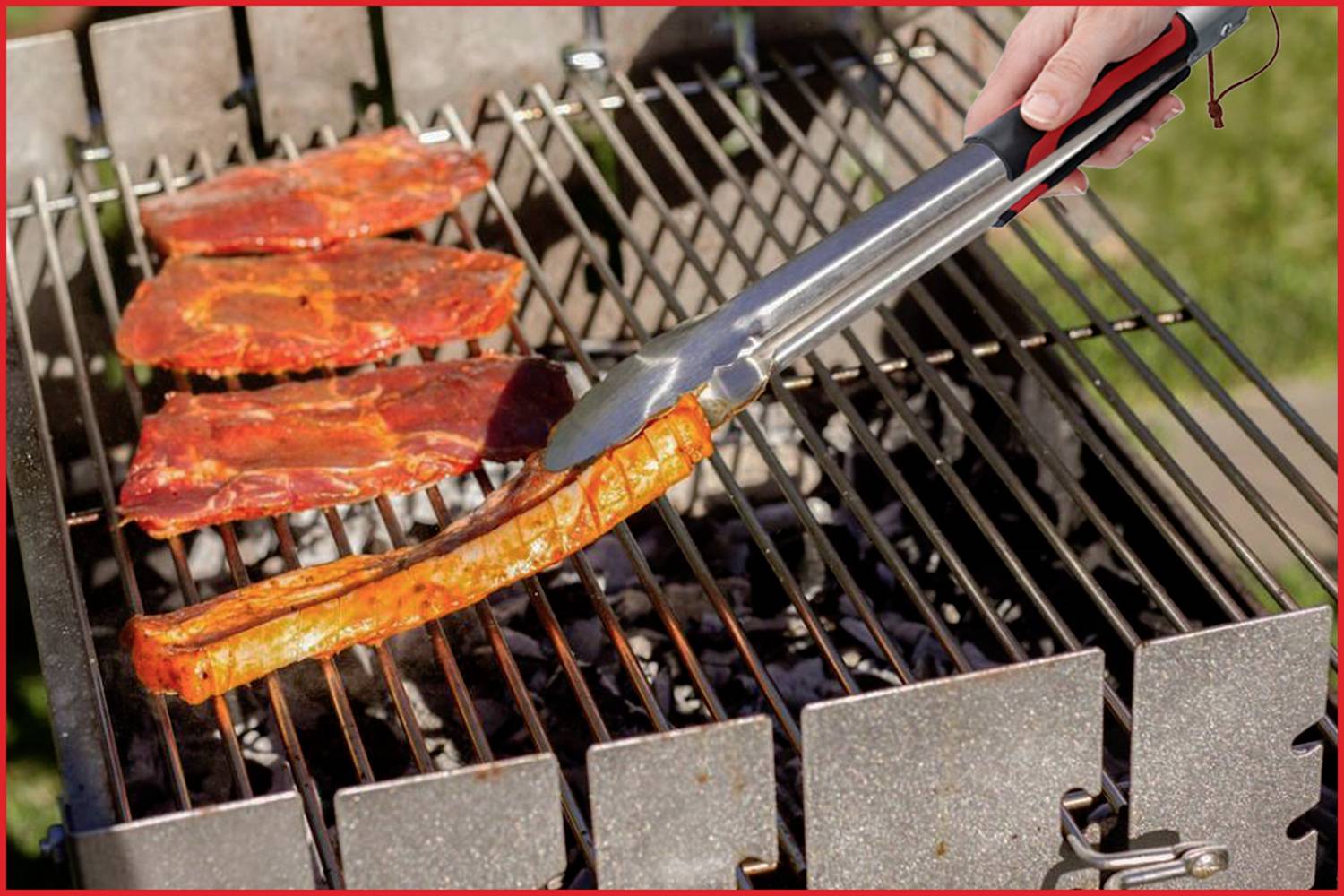 Eine Hand wendet mit einer Grillzange mariniertes Fleisch auf einem Holzkohlegrill. Es ist ein sonniger Tag im Freien.