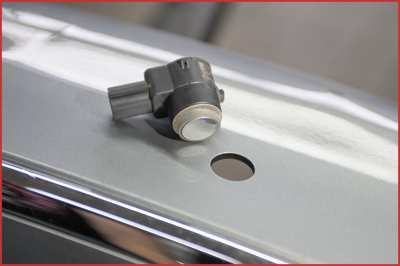 Ein Sensor neben einem Loch in einer Metalloberfläche. Der Sensor scheint zur technischen Montage vorgesehen zu sein.