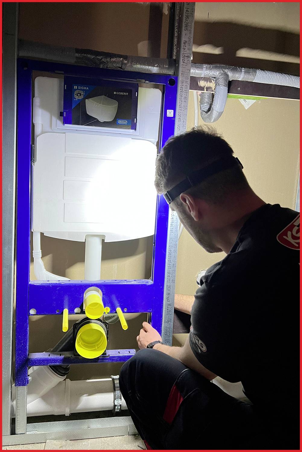 Ein Mann arbeitet an einer installierten Unterputztoilette in einem Rohbau. Er trägt eine Stirnlampe und Werkzeuge sind sichtbar.