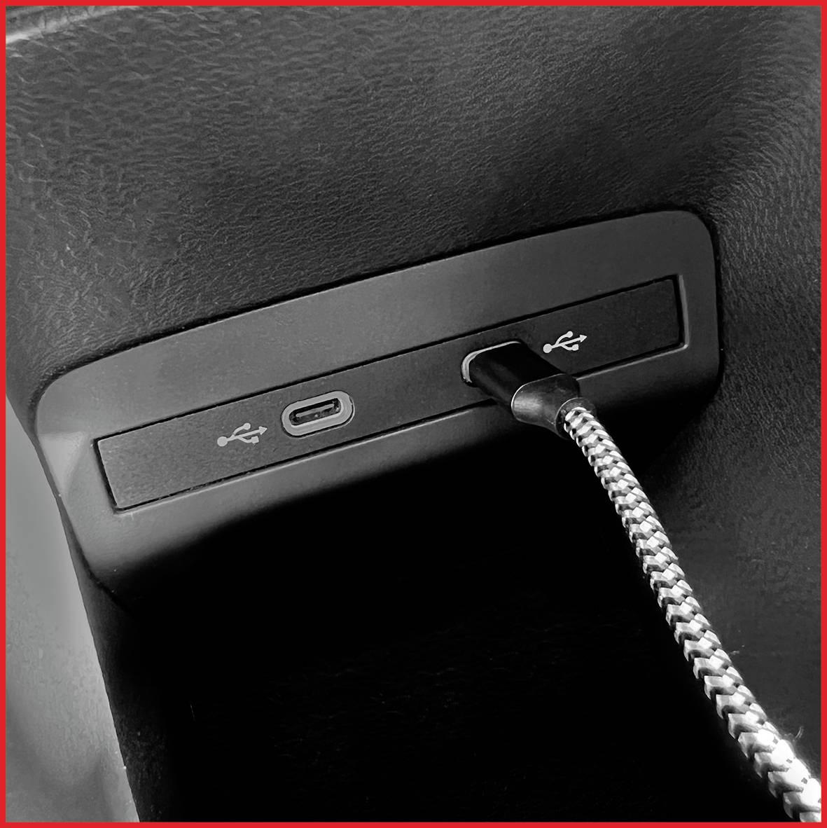 USB-Anschluss in einem Auto mit eingestecktem geflochtenem Kabel zu einer USB-C-Buchse.