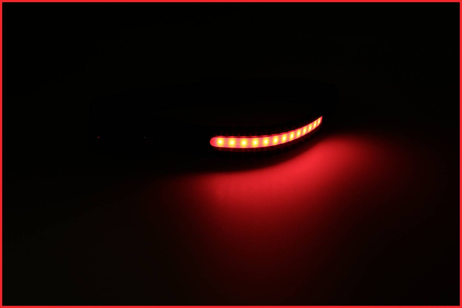 Ein leuchtendes rotes LED-Band in einer dunklen Umgebung, das eine gebogene Linie bildet. Es strahlt intensives rotes Licht aus.