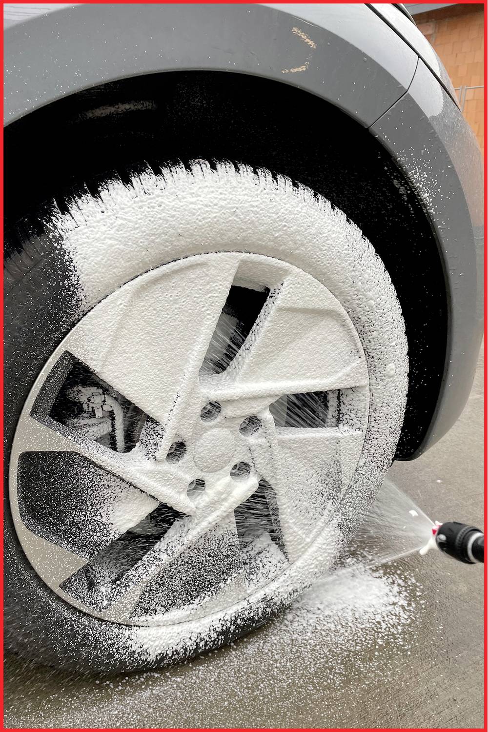 Auto wird gereinigt. Ein Reifenspray wird auf einen Autoreifen aufgetragen, um Schmutz zu entfernen. Nahaufnahme des Reifens.