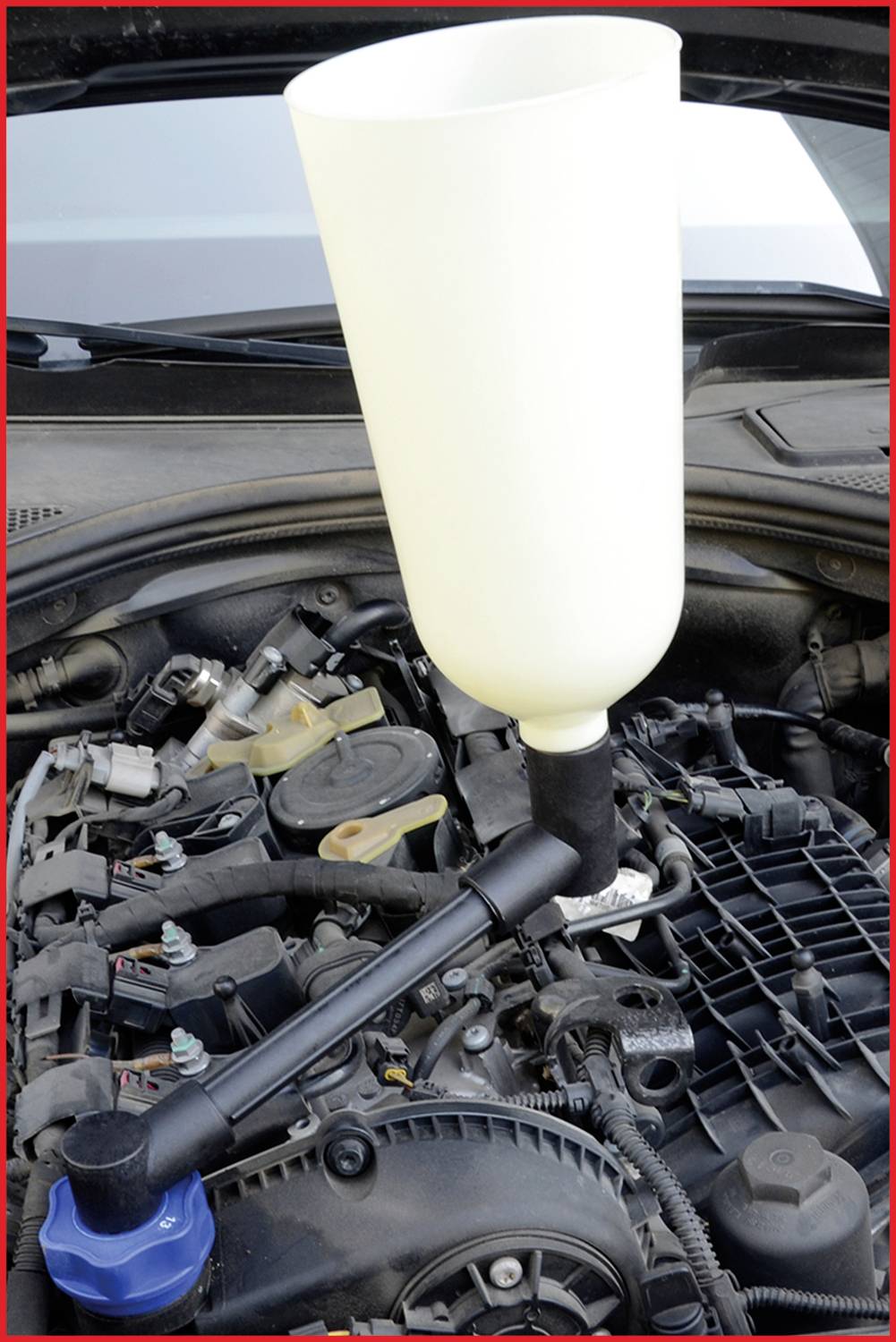 Trichter zur Ölauffüllung auf einer offenen Motorhaube eines Autos platziert.