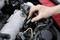 Eine Hand repariert oder inspiziert den Motor eines Autos, indem sie Teile des Motors unter dem geöffneten Deckel justiert.