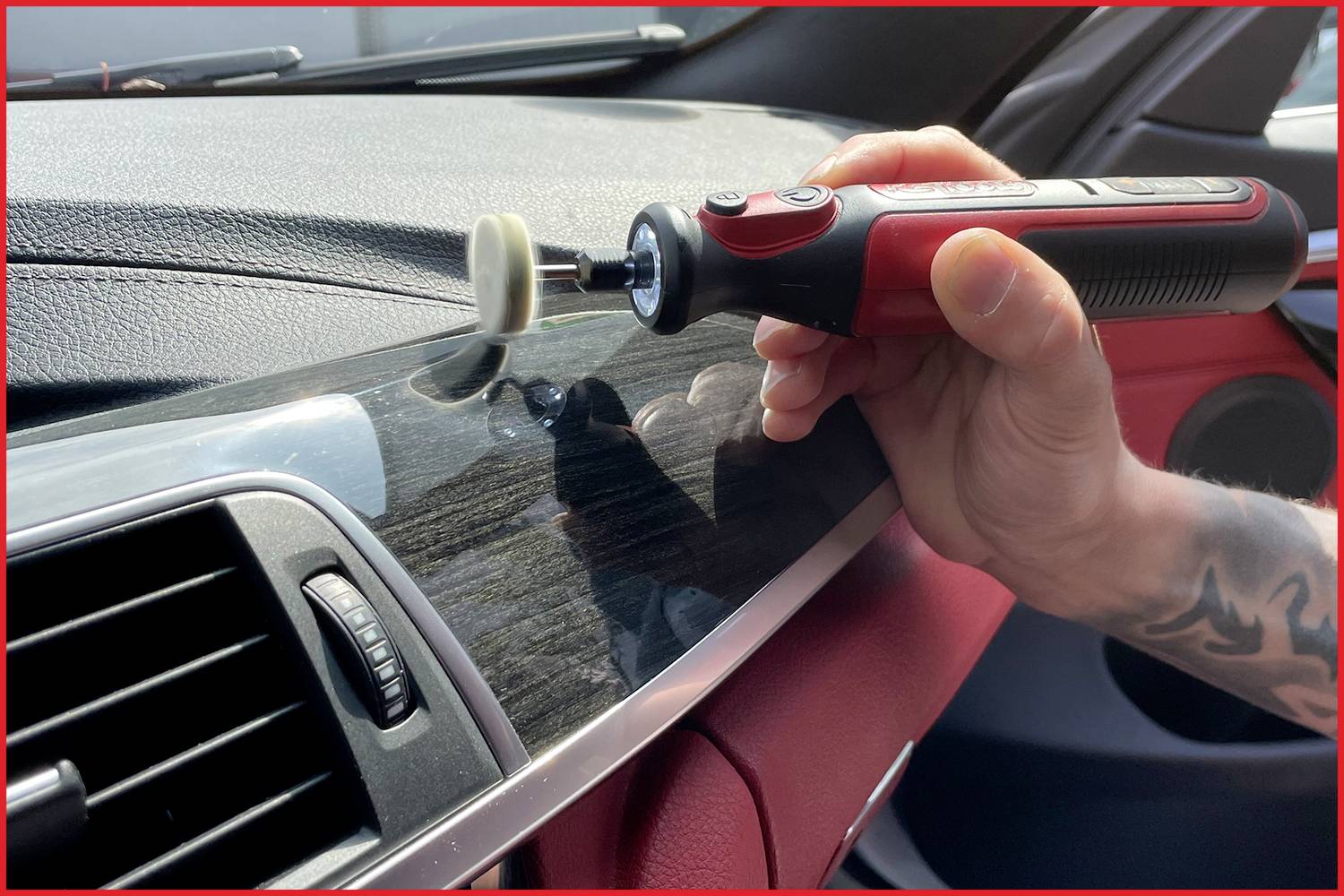 Person poliert mit einem elektronischen Gerät das Armaturenbrett eines Autos, um die Oberfläche zu reinigen und zu glätten.