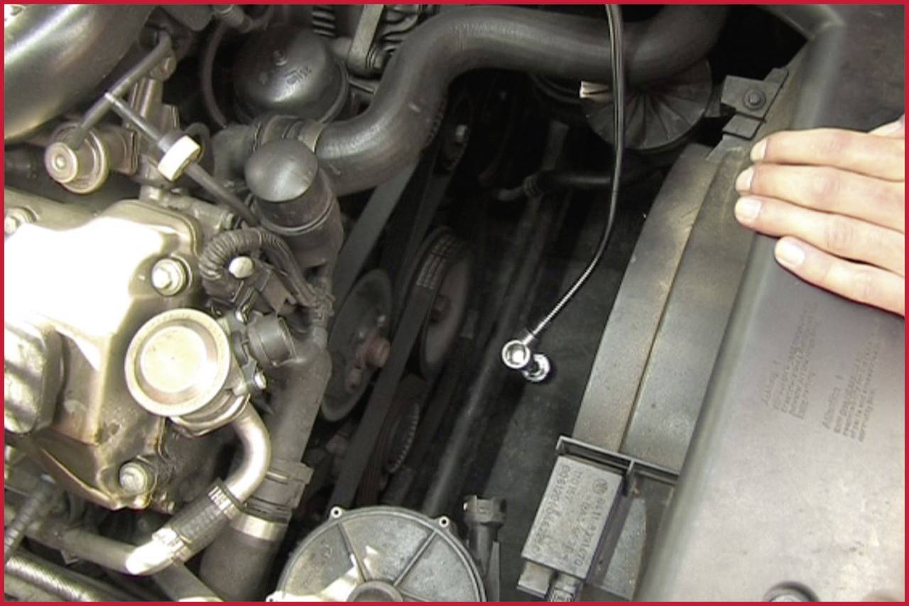 Motorteil eines Fahrzeugs mit sichtbaren Riemen und Hand, die auf die Motorabdeckung legt. Atmosphärische Motoransicht.