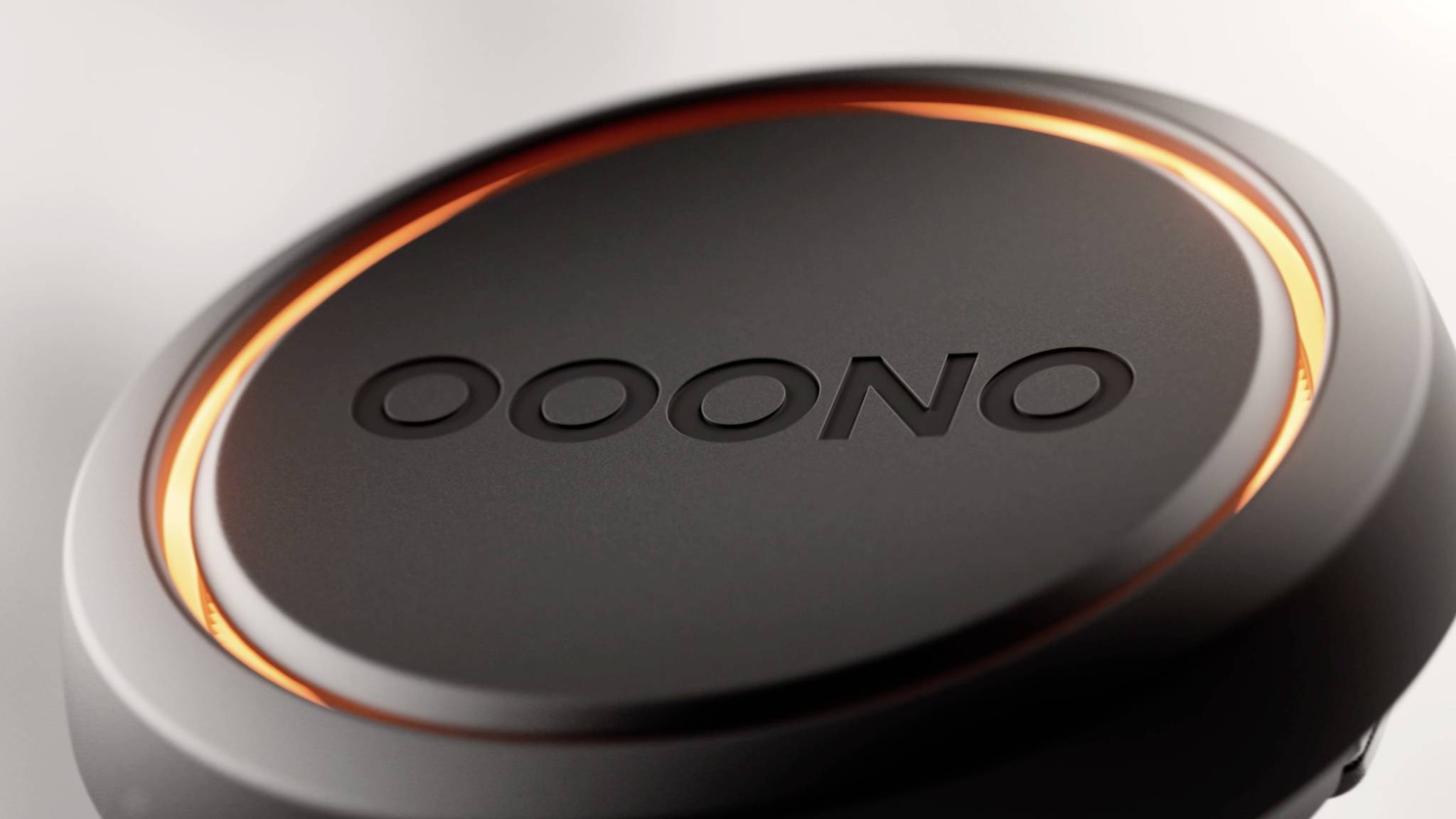 Schwarzer, runder Knopf mit dem Text 'OOONO' in der Mitte, von einem leuchtend orangefarbenen Ring umgeben.