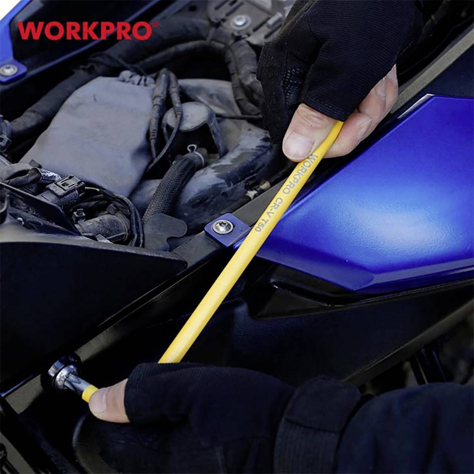 Zwei Hände, die mit einem gelben Bleistift unter eine blau-schwarze Maschinenabdeckung greifen, um an einer Schraube zu arbeiten.