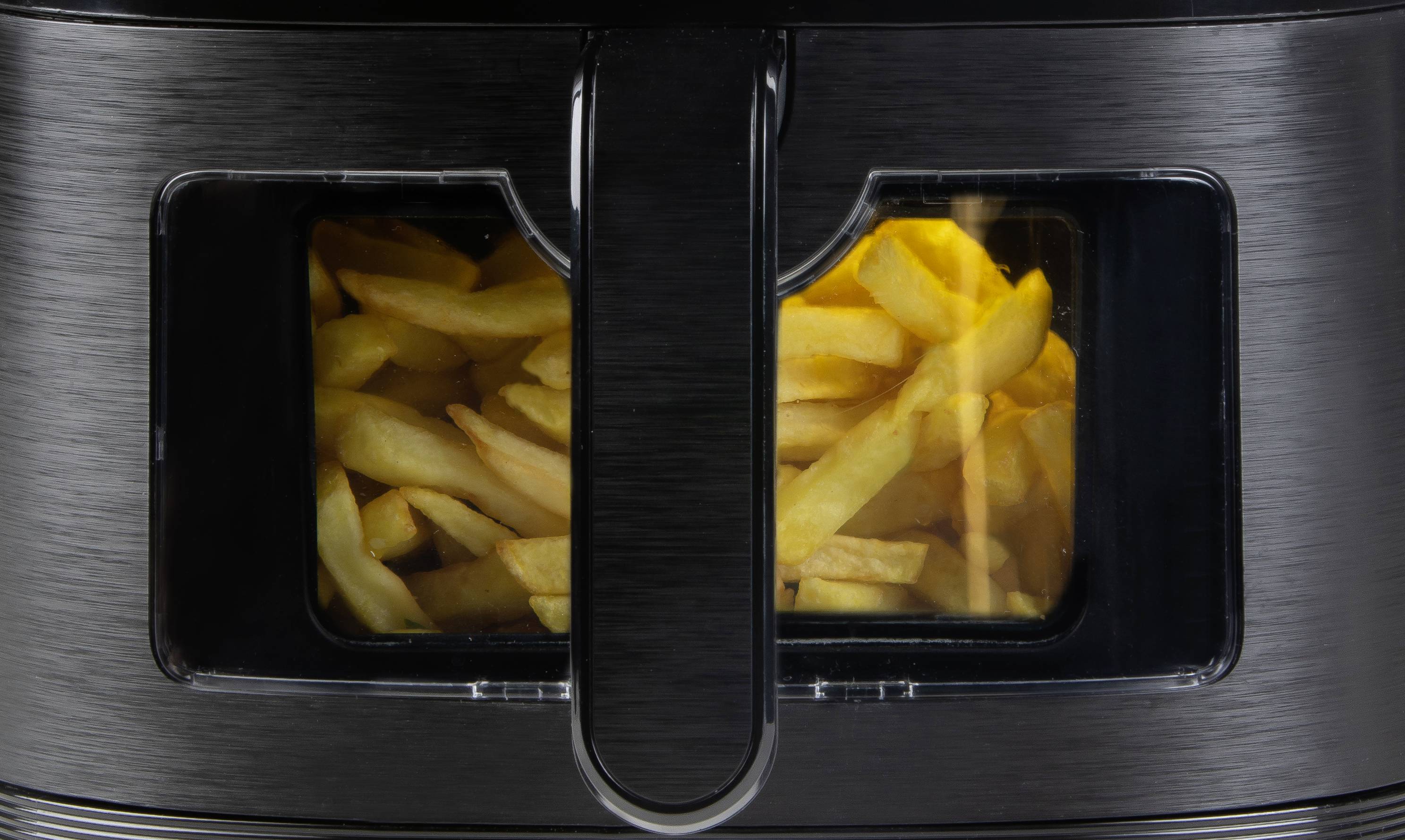 Frittierte Pommes frites in einer Heißluftfritteuse während des Kochvorgangs, sichtbar durch ein Sichtfenster an der Vorderseite.