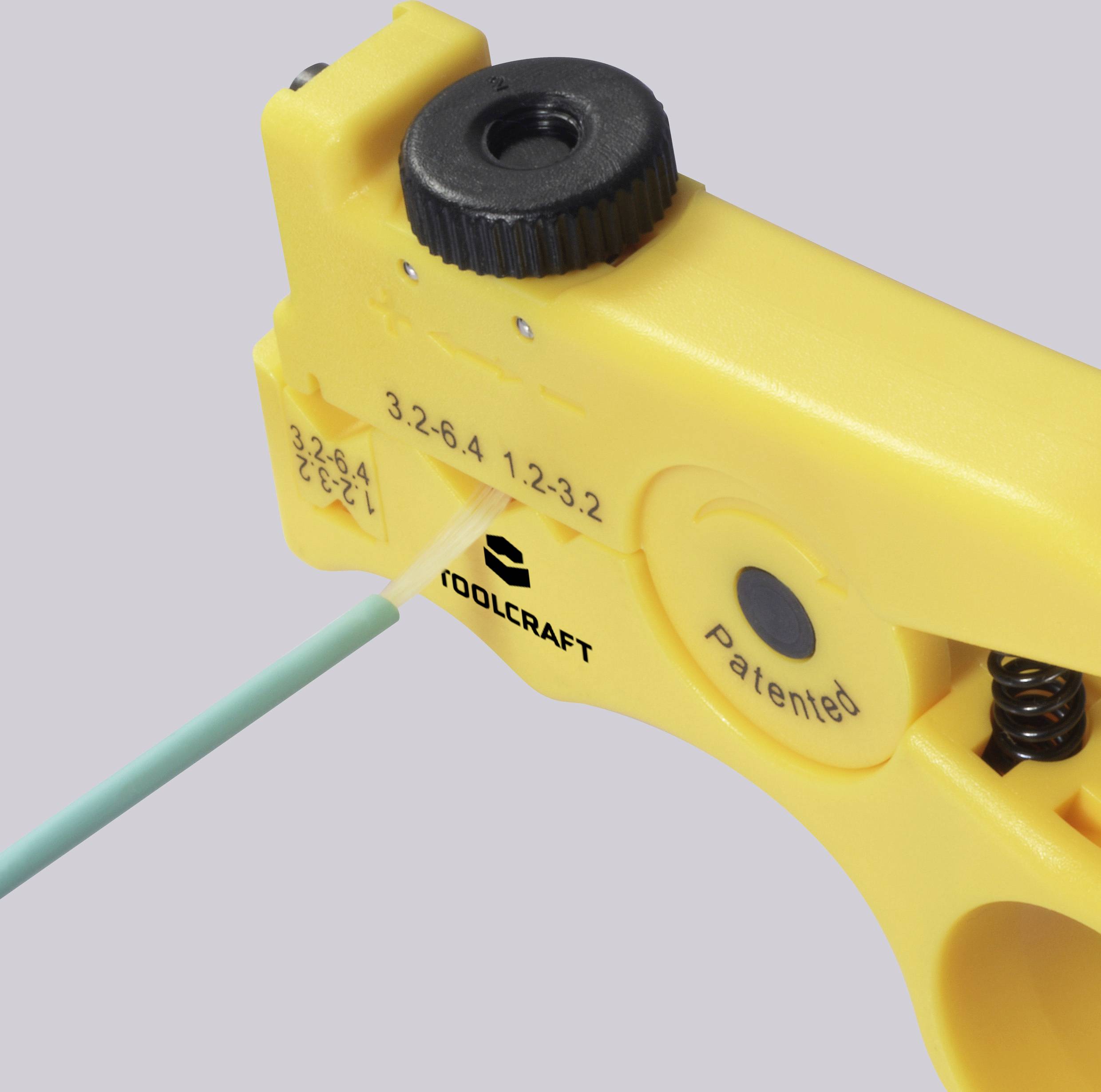 Gelbes Abisolierwerkzeug mit Messskala, auf dem 'TOOLCRAFT' und 'Patented' stehen, zeigt ein Kabel, das gerade abisoliert wird.