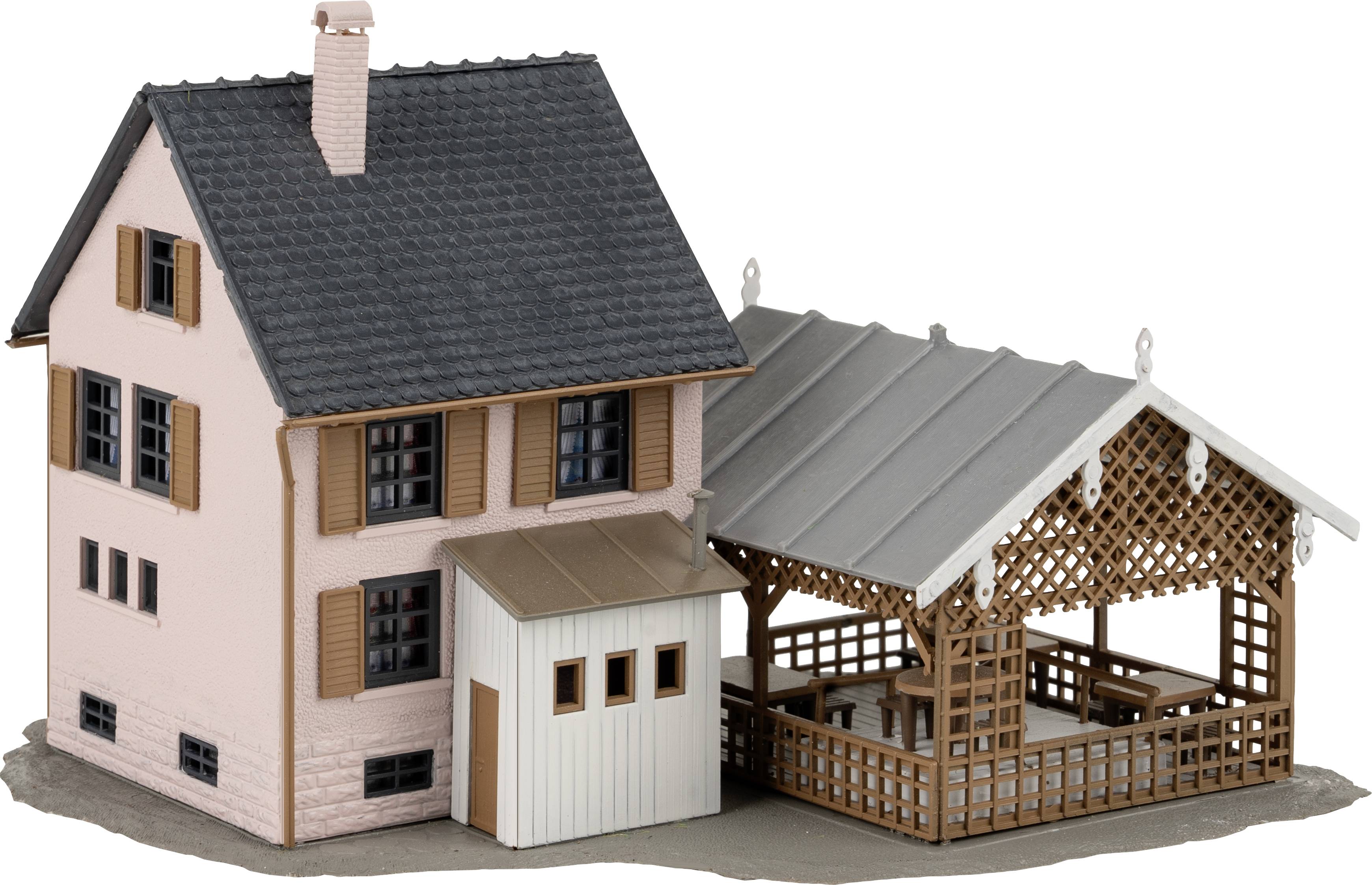 Ein kleines, detailreiches Modellhaus mit einem angebauten Carport aus Holzgittern und einem Schuppen.