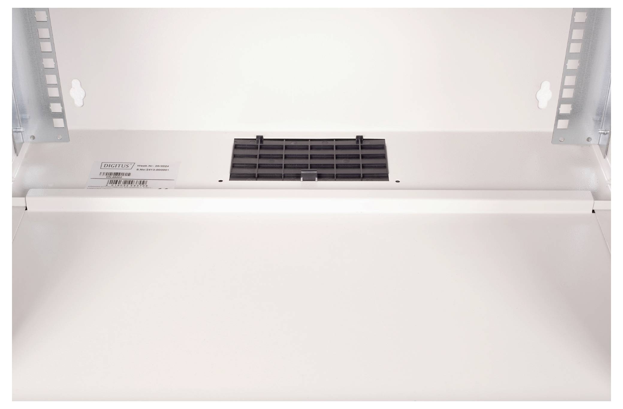 Ein offener Küchenschrank von unten mit Lüftungsgitter, sichtbar sind metallene Regalschienen und eine Lichtquelle.