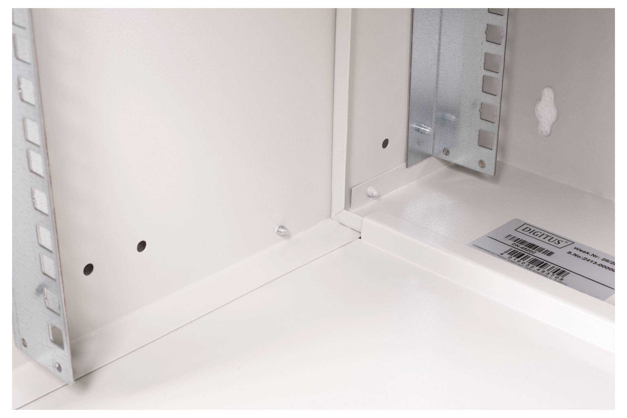 Detaillierte Innenansicht eines weißen Metallschranks mit Metallstreben und einem Etikett.