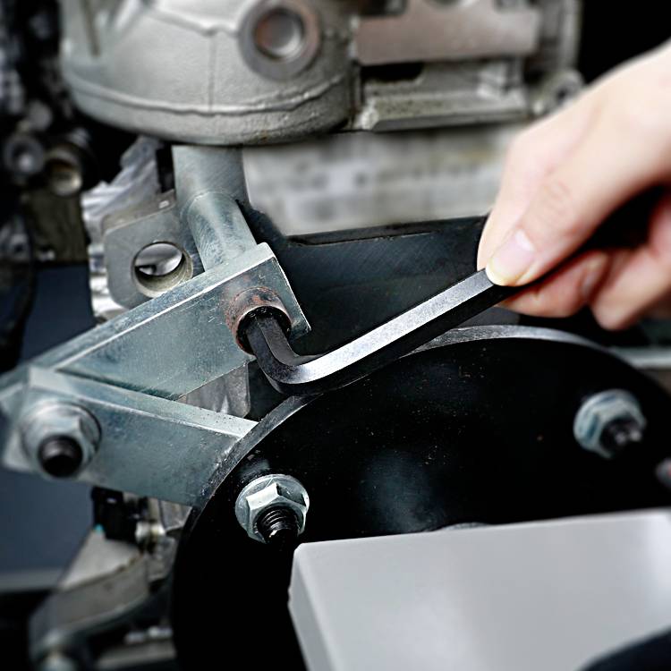 Eine Person zieht mit einem Inbusschlüssel eine Schraube an einer Metallmaschine fest, um die Wartung oder Reparatur durchzuführen.