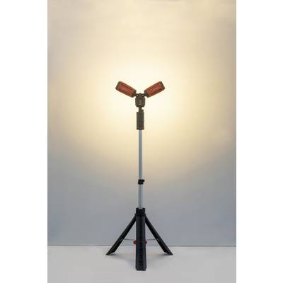 Eine duale LED-Arbeitsleuchte auf einem dreibeinigen Stativ leuchtet einen Raum mit warmem Licht aus, geeignet für Bauprojekte.