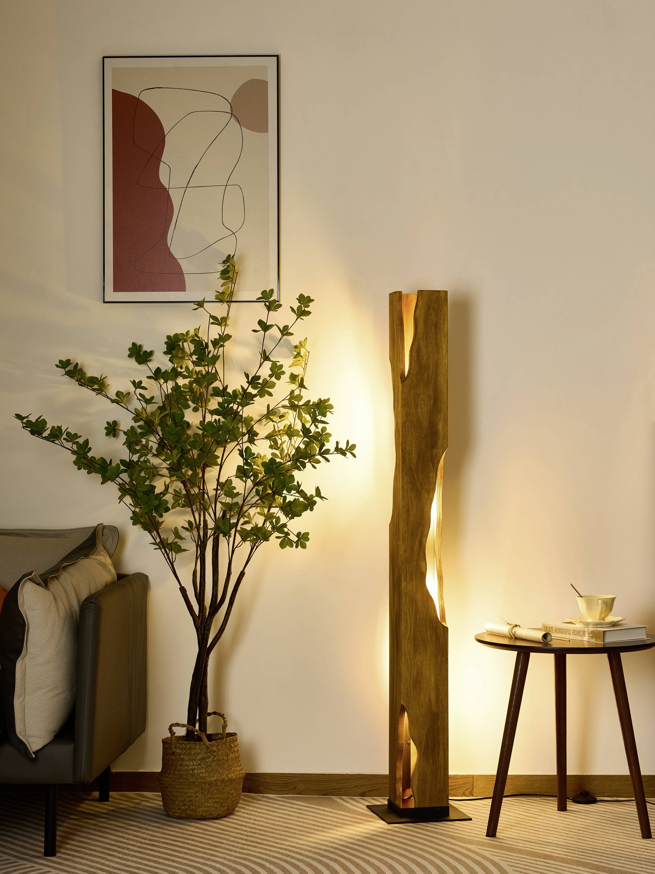 Eine moderne Wohnzimmer-Ecke mit Pflanze in Korb, abstraktem Kunstwerk an der Wand, und einer hohen, leuchtenden Stehlampe.