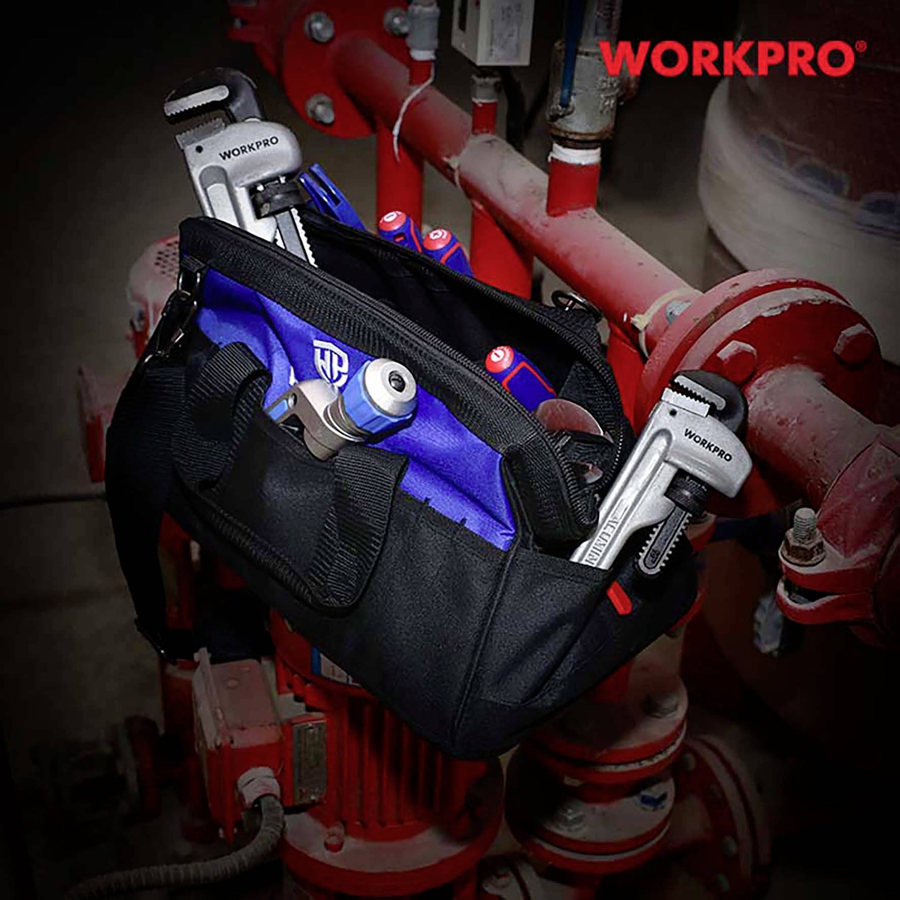 'WORKPRO' Werkzeugtasche gefüllt mit Werkzeugen, darunter Schraubenschlüssel und Zangen. Sie hängt an einem industriellen roten Ventil.