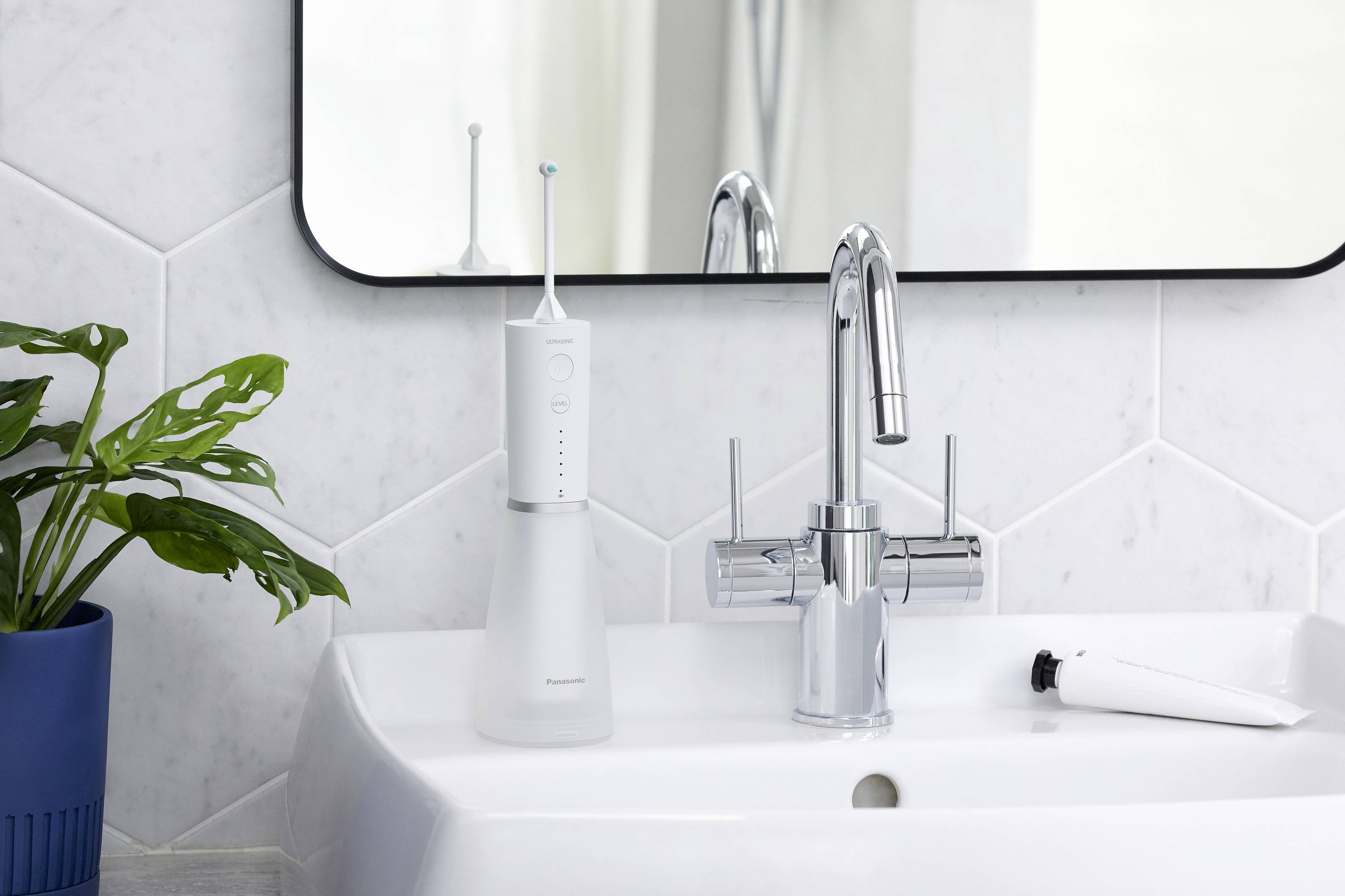 Ein Badezimmer mit einem Waschbecken. Auf dem Rand steht eine elektrische Zahnbürste und daneben eine entleerte Tube Zahncreme.