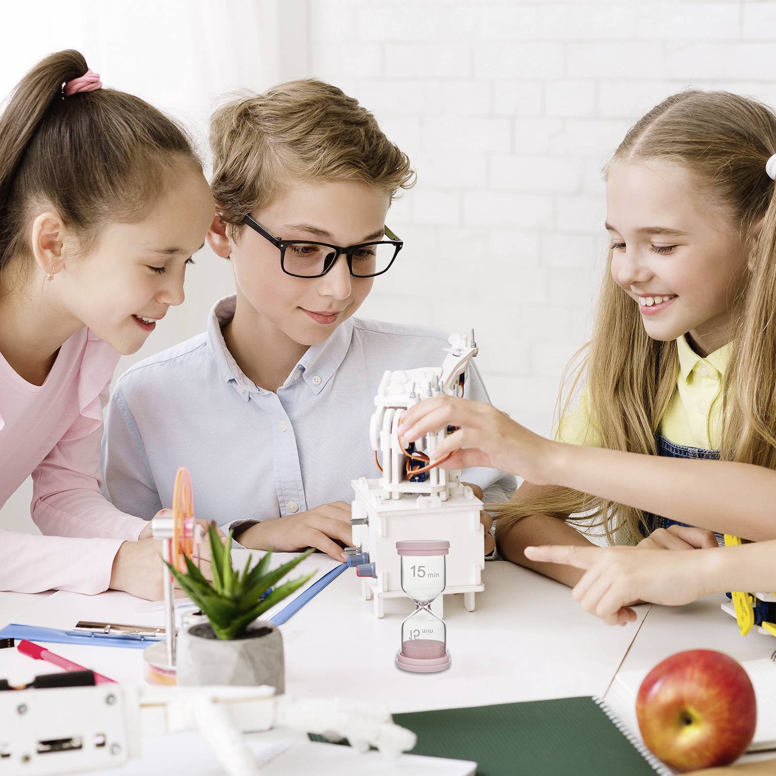 Drei Kinder arbeiten an einem Roboterprojekt auf einem Tisch mit Werkzeugen und Notizen. Ein Kalender zeigt den 15. Juni.