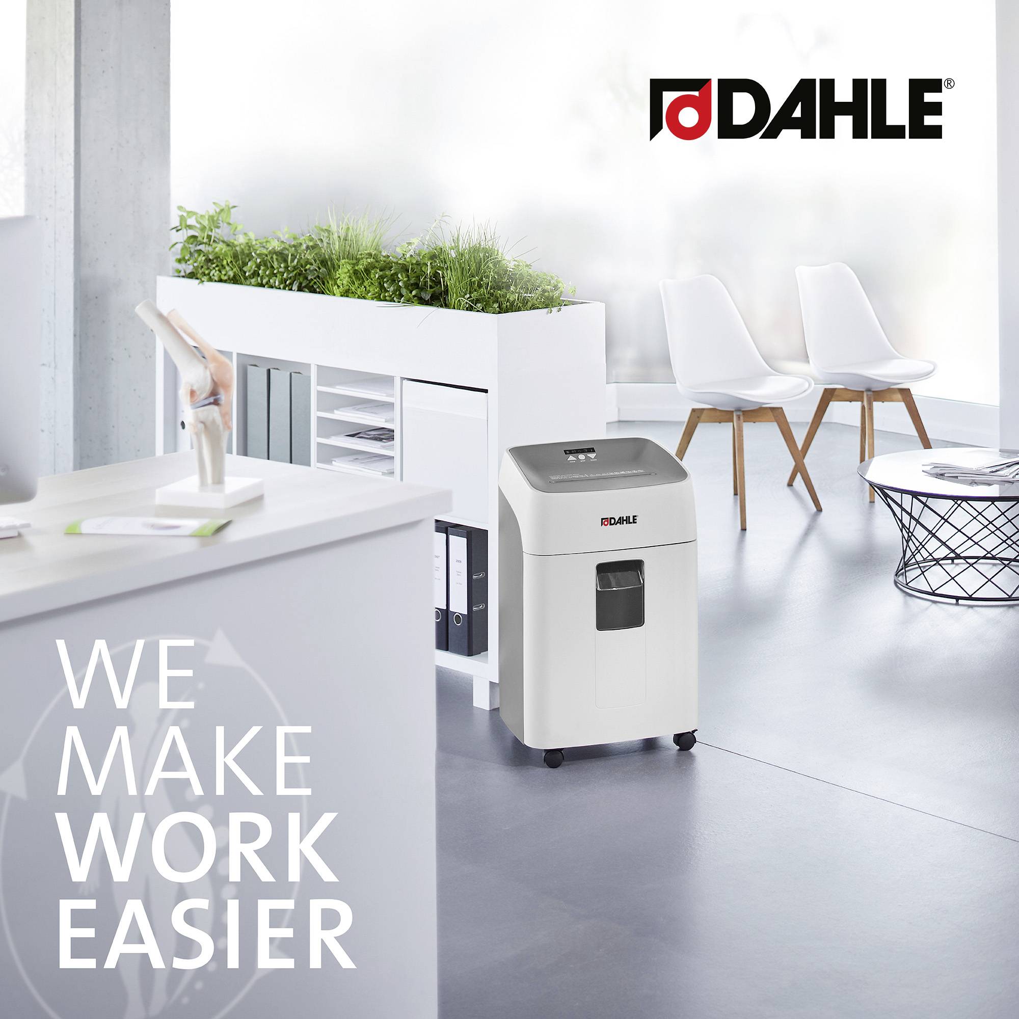 Büro mit Aktenvernichter und Pflanzen. Text auf dem Bild: 'We make work easier'. Möbel und Arbeitsbereich im Hintergrund.