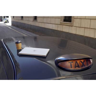 Ein Taxi in städtischer Umgebung mit einer Tasse Kaffee und einem aufgeklappten Laptop auf dem Dach.